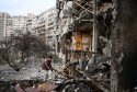 A man clears debris at a damaged residential building in Ukraine